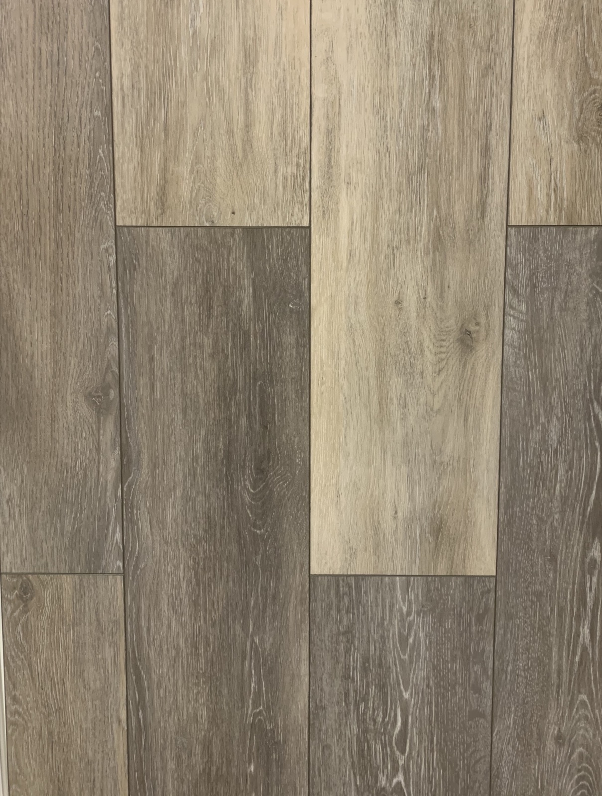 A close-up of luxury vinyl plank in mixed warm and driftwood tones, laid in a natural staggered pattern — waterproof and hard-wearing.